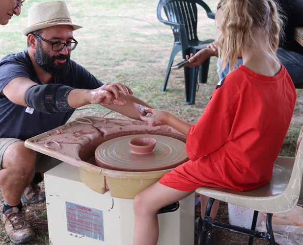Démonstration de tournage de poterie : un enfant s'essaie au tour lors d'une animation en plein air